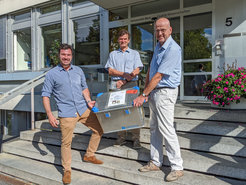 Philipp Heumüller (left) and Dr. Markus Fränz (right) from MPS hand over the transport box with the JUICE sensor JEI to Prof. Dr. Peter Wurz (centre), Head of Division "Space Research and Planetology" at the University of Bern.